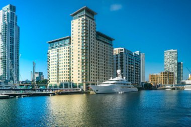 Güneşli bir günde mavi gökyüzü, ofis binaları, gökdelenler, Thames nehri, yat, marina ve Londra Kanarya Rıhtımı 'nın iş bölgesindeki konut binalarına yansıyor. Web siteleri ve broşürler için kullanılabilir.