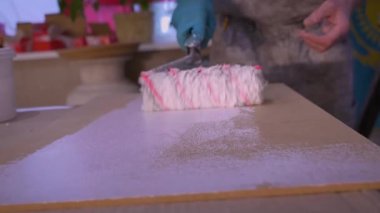 Erkek işçiler yüzeyde bir silindirle resim yapar ve doku oluştururlar.