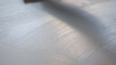 İşçi yüzeye dekoratif alçı uygular. İnşaatçı bir spatula, çizgiler ve lekelerle yüzeyde kalır.