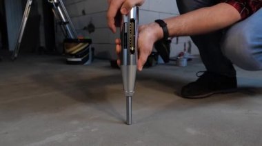 Adam mekanizmayı elinde tutuyor ve yere koyuyor. Yıkıcı olmayan beton testi. Somut dayanıklılık ve yapışkanlık testi, sklerometre