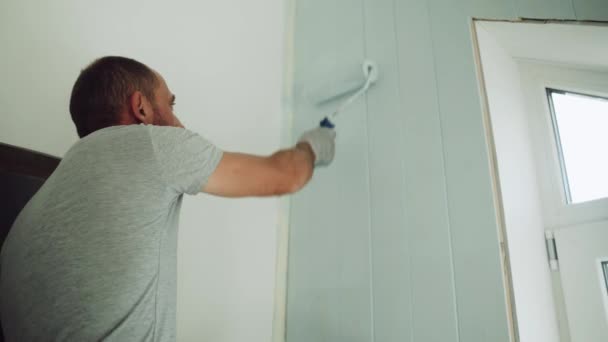 Mężczyzna maluje ścianę wałkiem. Człowiek dokonuje napraw w pokoju. Nowoczesne wnętrze w domu. Piękny design poddasza. Samoizolacja. Kwarantanna. Wysokiej jakości naprawy — Wideo stockowe