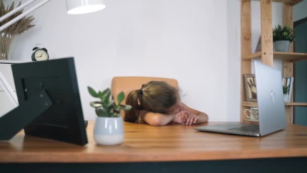 A rapariga olha para o portátil. A criança se comunica online enquanto está sentada à mesa. A criança aprende online. Educação doméstica. A luz de uma lâmpada de mesa. Treinamento online Auto-isolamento Movimento lento — Vídeo de Stock