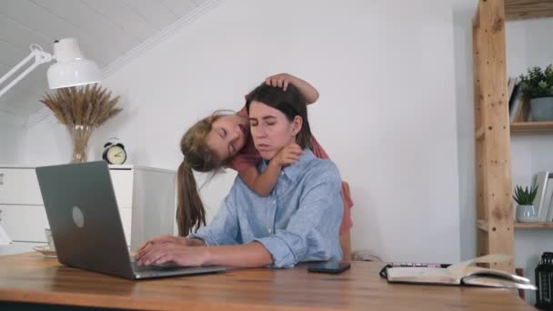 子供のいる女性がノートパソコンで働いている。その女性は疲れて目を閉じていた。その少女は母親が働かないようにしている。疲労だ。ストレスだ。フリーランス。自己分離。自宅で働く｜スローモーション — ストック動画