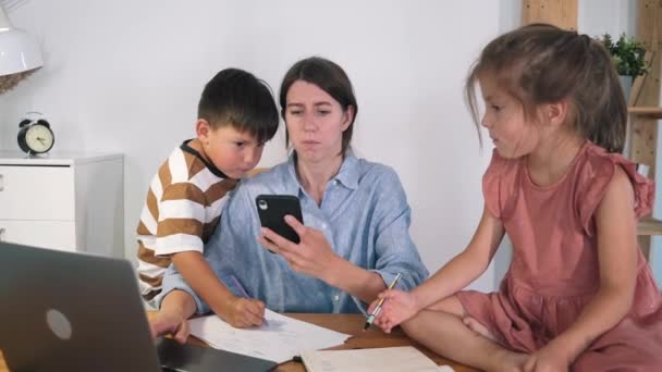 En kvinna med barn jobbar på en bärbar dator. Barnen hjälper sin far att arbeta. Familjeangelägenheter. Frilans. Självisolering. Coronavirus. En epidemi. Arbete i hemmet — Stockvideo