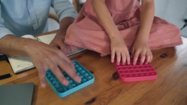 Bir adam ve bir çocuk Poppit oynuyorlar. Bir adam ve bir kız, Poppit Bubbles 'a tıklayarak 2021' in popüler kendini izole etme eğilimli oyuncağı ile rekabet ediyorlar. Aile, ofiste Poppit oynuyor.