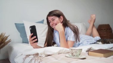 Bir kadın yatakta yatarken internette konuşuyor, bir kadın öpücük yolluyor. Uyuyan kedi. Bir kadında güzel pijama. Bir fincan kahve... bir buket kurutulmuş çiçek... rahat bir yatak. Yavaş çekim