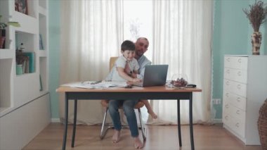 Ebeveyn evde çalışıyor. Uzaktan kumanda. Aile bireysel izolasyonda. Merkez ofis. Baba ve oğul bilgisayar oynayarak eğleniyorlar. Mutlu bir çocukluk. Babalık. Karantinaya alın. Salgın hastalık. Kriz.