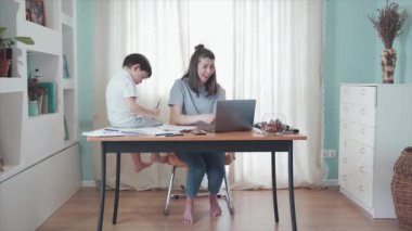 Annem evde çalışıyor, masada oturuyor. Masada oturan küçük bir çocuk. Anne ve oğlu birlikte iyi vakit geçiriyorlar. Uzaktan kumanda. Aile bireysel izolasyonda. Merkez ofis. Beş veriyor. Karantinaya alın. Salgın.