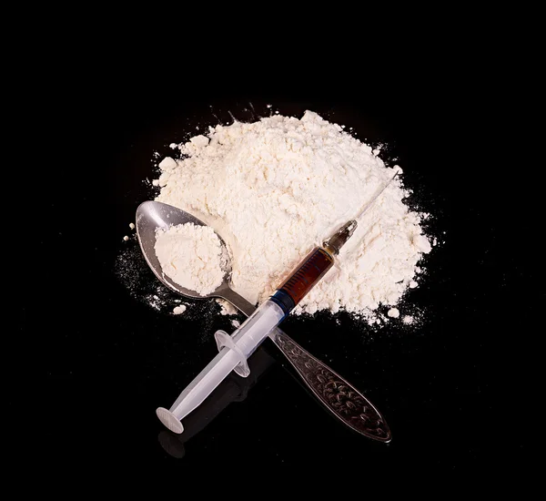 Pó da droga, seringa da droga e droga na colher close-up em um fundo preto . — Fotografia de Stock