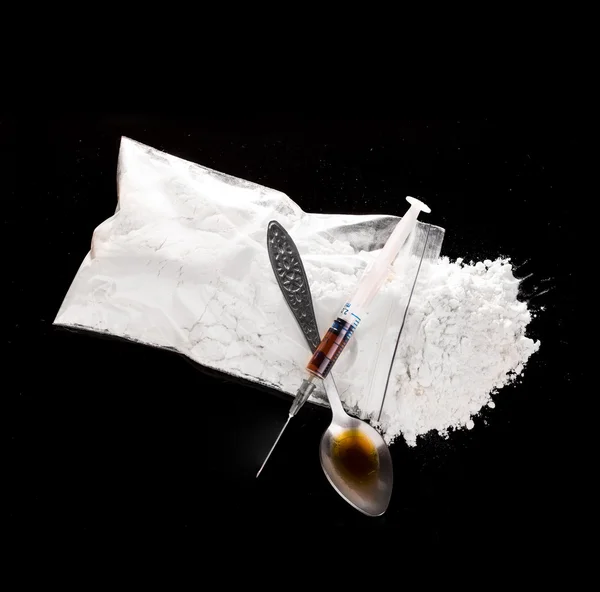 Polvo de la droga, jeringa de la droga y droga cocida en el primer plano de la cuchara en un fondo negro . — Foto de Stock
