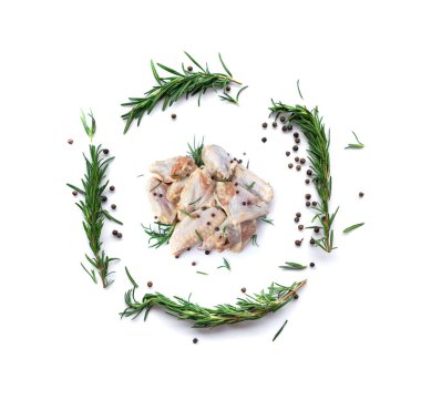 Beyaz arka planda sarımsak, biber ve biberiyeli çiğ tavuk kanadı.