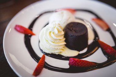 Vanilyalı ve taze çilekli sıcak çikolatalı kek resmi.