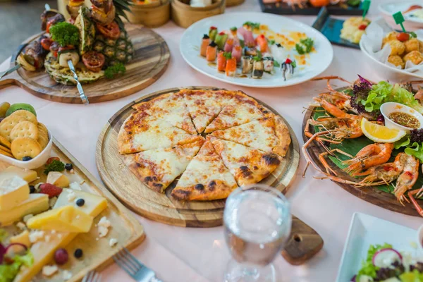 Yemek takımı, pizza, deniz ürünleri ve suşi ile birlikte yemek masasının resmi.