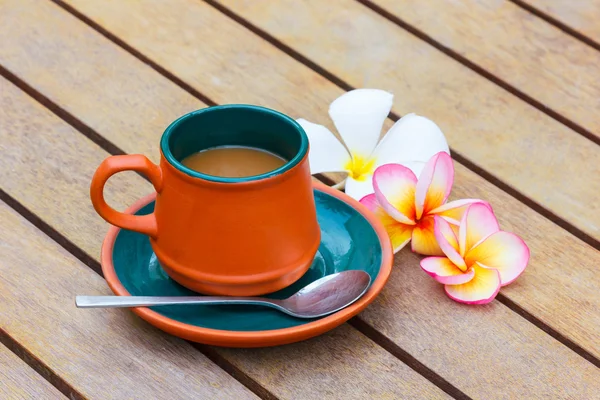 Sıcak kahve kil Kupası ve Plumeria çiçek ahşap tablo.