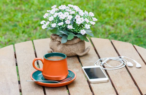 Warme koffie en hoofdtelefoon en slimme telefoon op de houten tafel. — Stockfoto