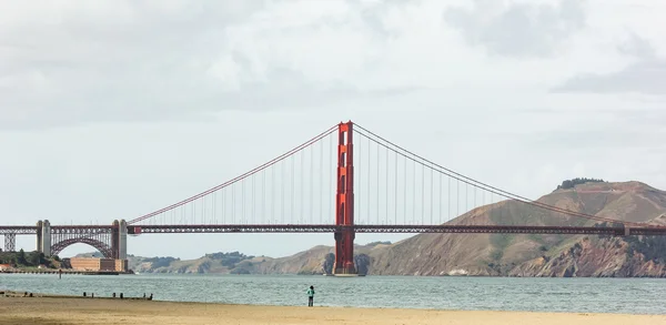 Egy nő áll a tengerparton és nézte a Golden Gate híd. — Stock Fotó