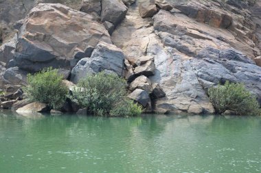 Çalılı kayalar ve dalgalı göl suyu