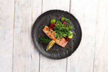 Siyah tabakta somon bifteği ve salata. Hafif bir arkaplanda. seçici odak