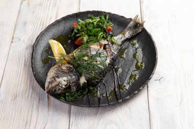 Salatalı Dorado balığı pişirdim. Siyah bir tabakta. hafif bir arkaplanda