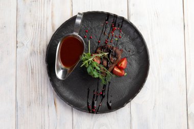 Tabakta mignon bifteği ve sos. Hafif bir arkaplanda.