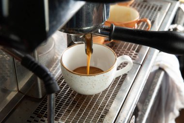 Kahve makinesi taze kahve hazırlıyor ve restoranda, barda ya da barda fincanlara dökülüyor..