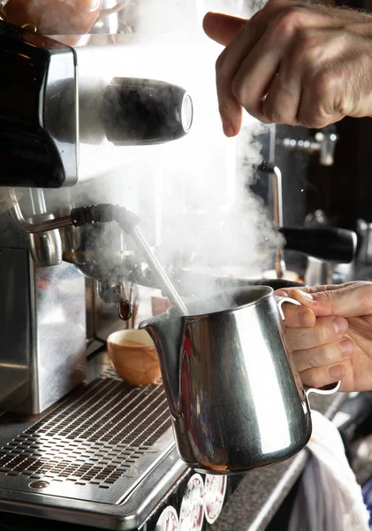 Yakın plan kadın elleri kafede profesyonel metal makine kullanarak kahve yapıyor. Barista sütü ısıtıyor köpüğü köpükle çırpıyor..