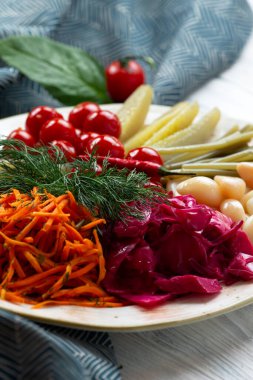 Bir tabakta çeşitli turşulu ve tuzlu sebzeler. Hafif bir arkaplanda.