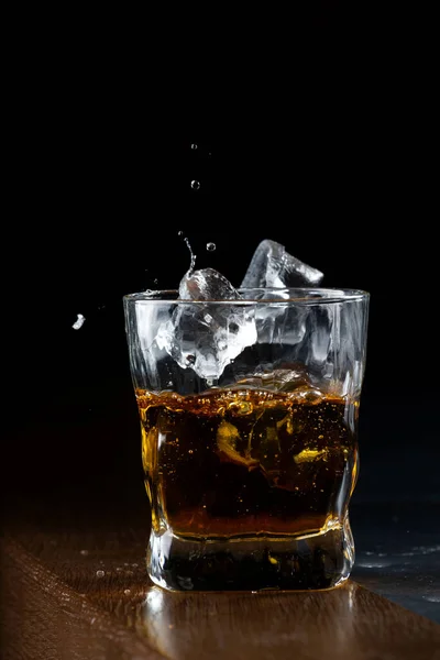 Лёд бросают в стакан виски — стоковое фото