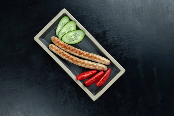 Fried sausages and fresh vegetables on a plate. — Stock Photo, Image