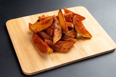 Tahtada patates parçaları. Karanlık bir arka planda