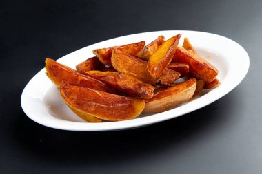 Tabakta patates parçaları var. Karanlık bir arka planda