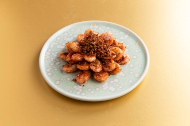 Sarı arka planda tabakta kızarmış karides.