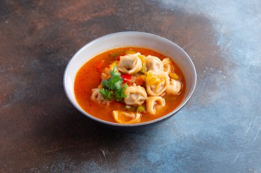 Geleneksel sıcak çorba, mantı ve sebzeler kasede.