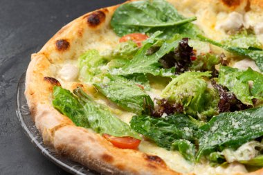 Tavuk, ot, domates ve peynirli pizza. koyu bir arkaplanda