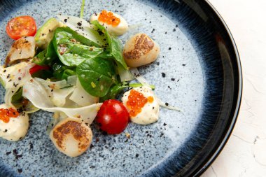 Kızarmış deniz tarağı, otlar ve kırmızı havyar. hafif bir arkaplanda