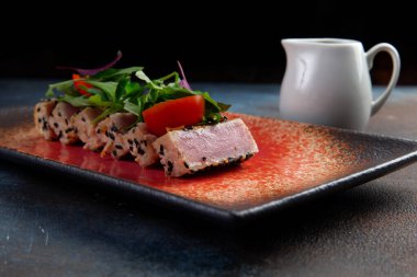 Taze domatesli kızarmış ton balığı, susam tohumu ve roka salatası. Seçici odak