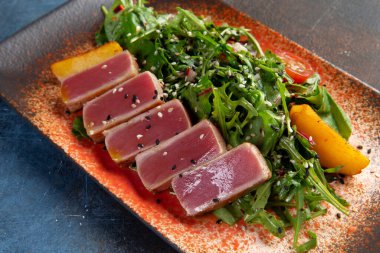 Taze domatesli kızarmış ton balığı, susam tohumu ve roka salatası. Seçici odak