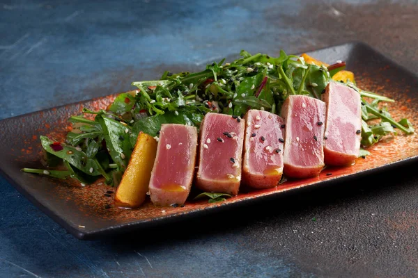 Taze domatesli kızarmış ton balığı, susam tohumu ve roka salatası. Seçici odak