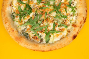 Sarı arka planda peynirli ve roka aromalı pizza. Seçici odak