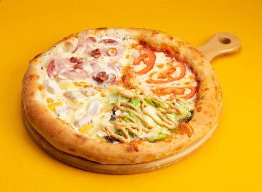 Türlü pizza. Domates, sosis, tavuk, ananas, salata Sarı arka planda Seçici odak