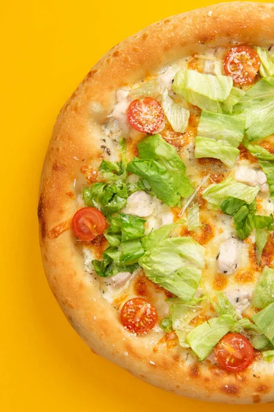Pizza with tomatoes and salad on a yellow background. Selective focus