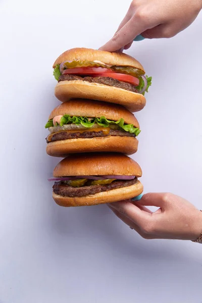 Las Manos Sostienen Tres Hamburguesas Diferentes Sobre Fondo Blanco Enfoque — Foto de Stock