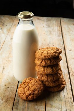 Tahta bir masada bir şişe süt ve bir yığın kurabiye. Seçici odak