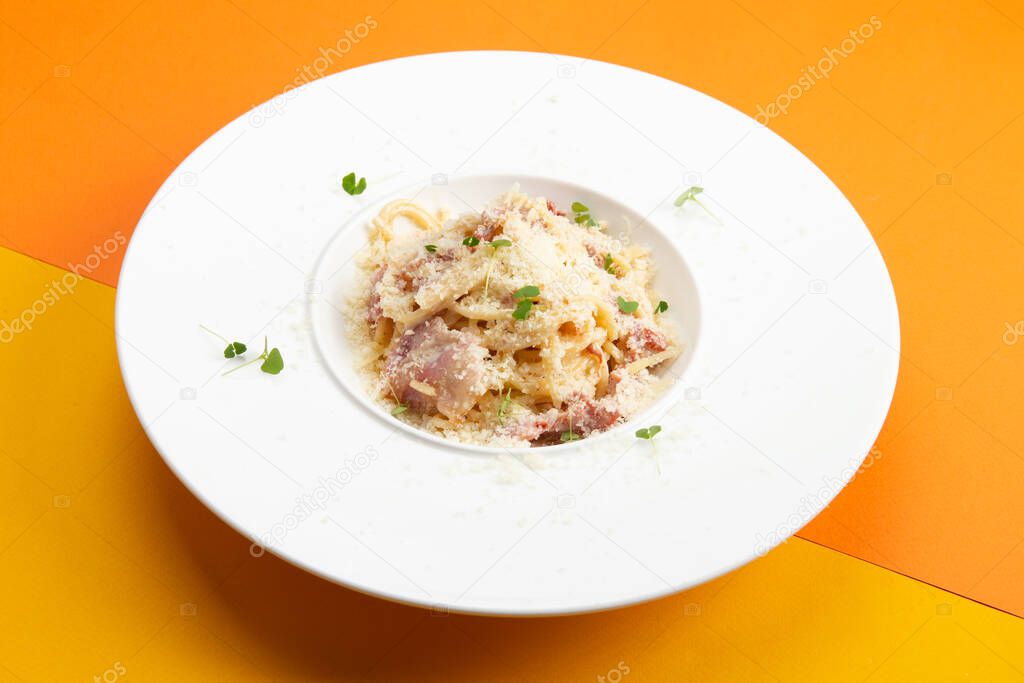 Corbanara pasta with bacon. In a plate on a colored background. Selective focus.