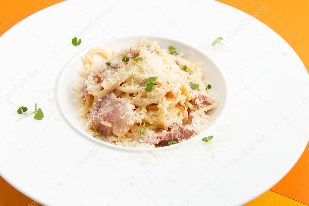 Corbanara pasta with bacon. In a plate on a colored background. Selective focus.