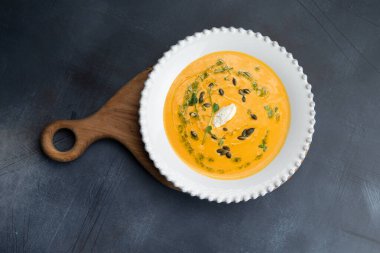 Gri arka planda bir tabakta balkabağı çorbası. Seçici odak.