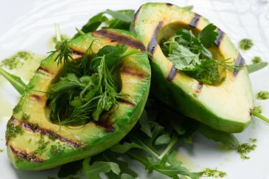 Gri arka planda kızarmış avokado ve yeşiller. Seçici odak.