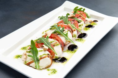 Tabakta Caprese. Mozzarella, domates ve roka. Gri bir arka planda. Seçici odak.