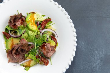 Tabakta et ve avokado ile salata. Gri bir arka planda. Seçici odak.