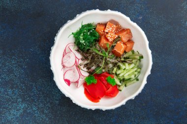 Bir tabakta somon, turp ve salatalık. Karanlık bir arka plana karşı. Seçici odak.